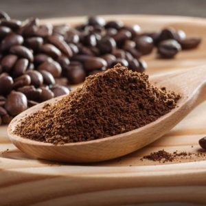 Coffee Ground coffee in wooden spoon. Coffee fried grain on wooden platter. Close-up. Coffee ground, coffee beans.